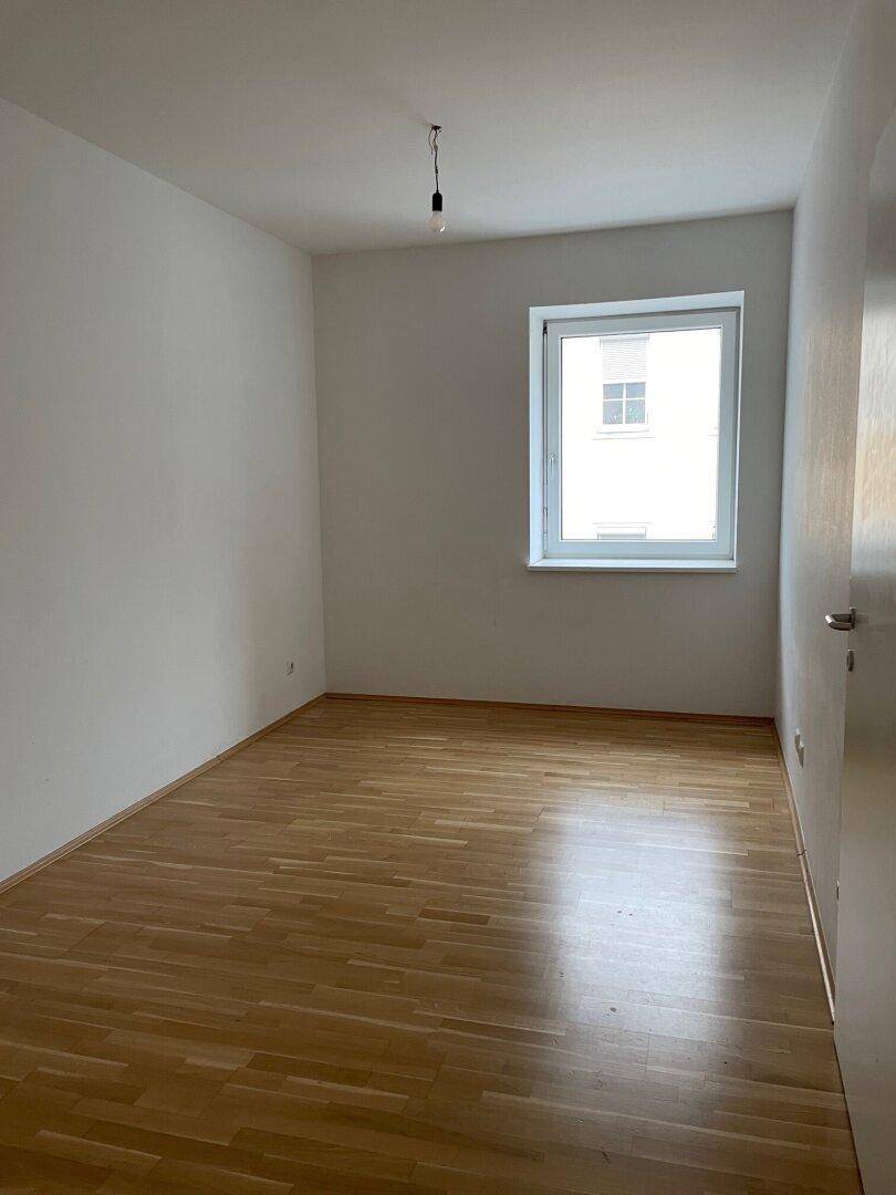 Helles Zimmer mit Holzboden und einem Fenster, das sich ideal als Schlaf- oder Arbeitszimmer eignet.