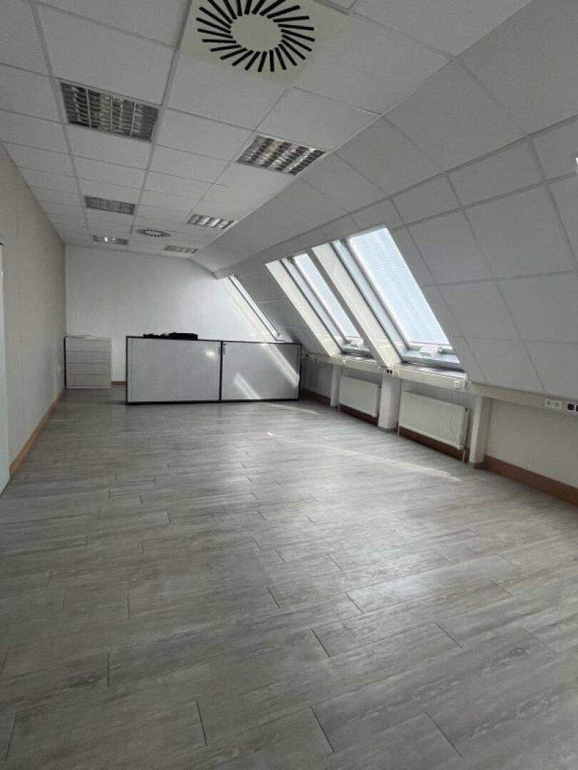 Helles und geräumiges Büro im Dachgeschoss mit schrägen Wänden und mehreren großen Dachfenstern.