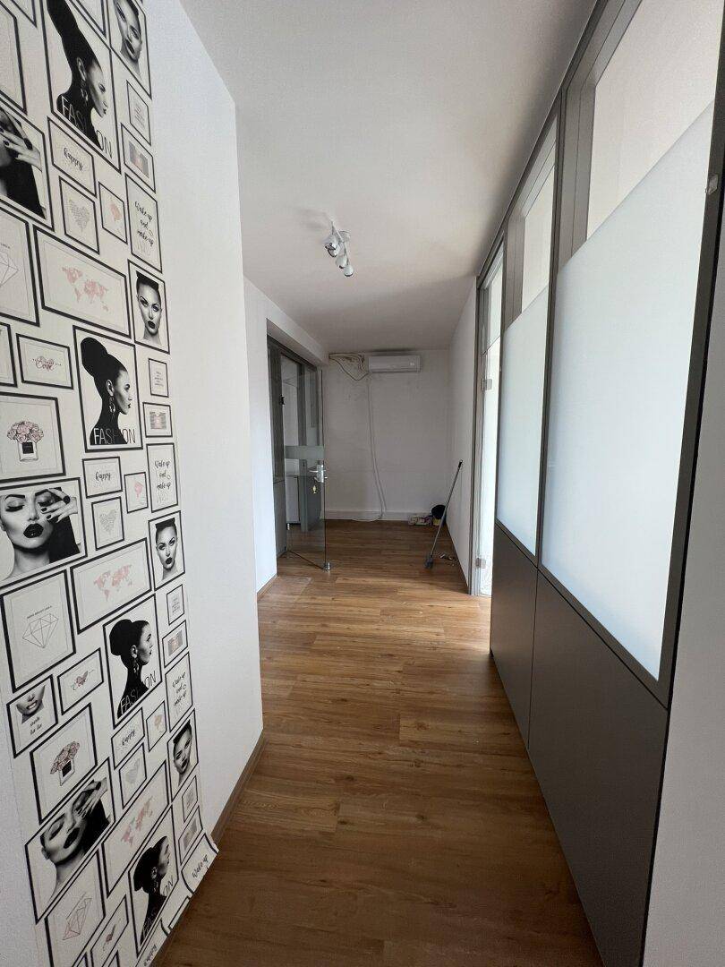 Langer Flur mit Holzboden und dekorativer Bilderwand, der zu weiteren Büroräumen führt.