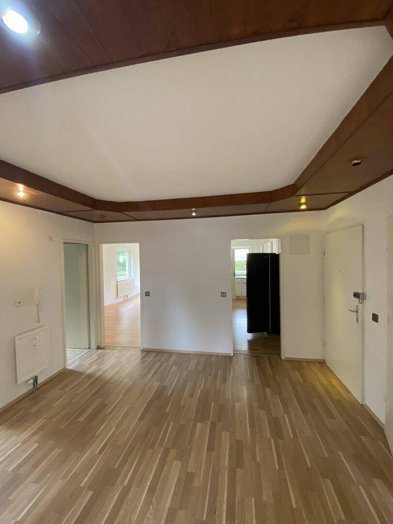 Heller Wohnbereich mit Laminatboden und einer dekorativen Holzdecke, die mehrere Räume verbindet.