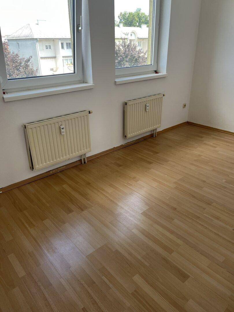 Helles Zimmer mit Parkettboden und zwei Fenstern, ideal als Schlaf- oder Kinderzimmer nutzbar.