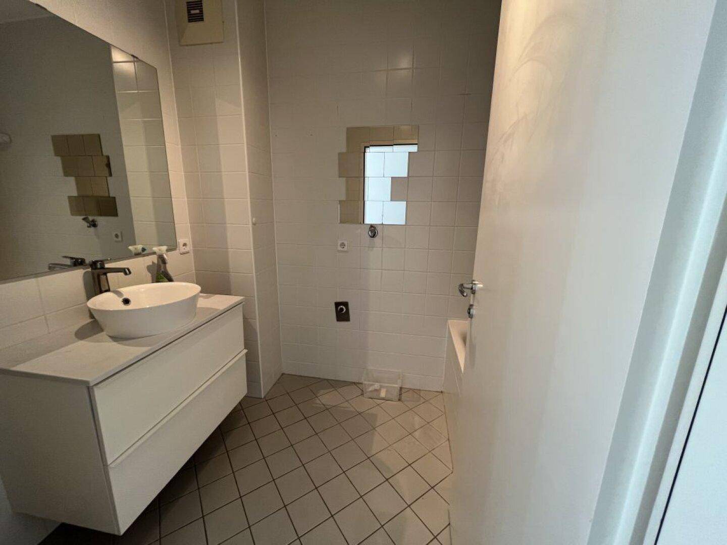 Modernes Badezimmer mit Aufsatzwaschbecken, großem Spiegel und Fliesenboden.