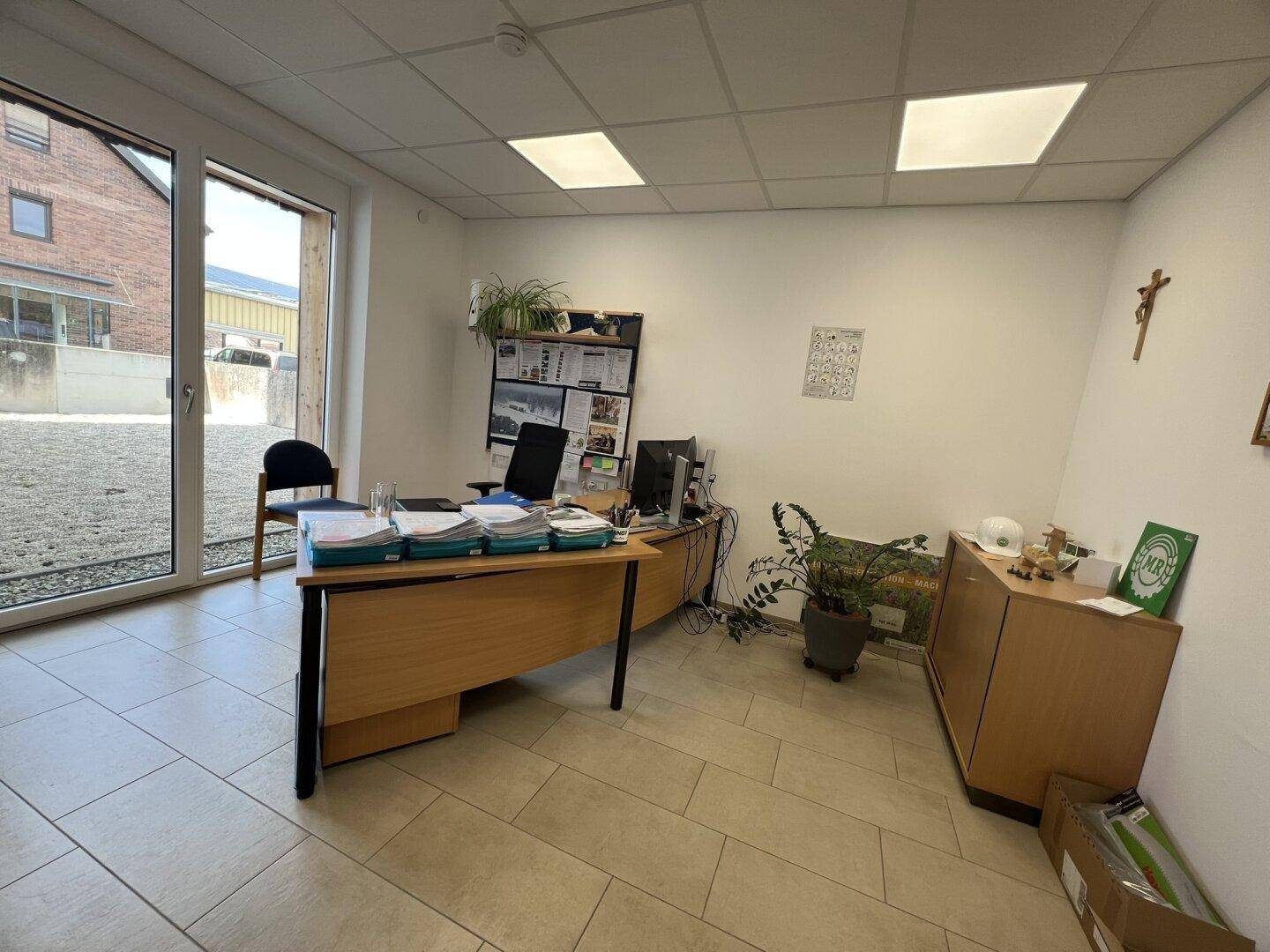 Büro mit großem Fenster, das viel Tageslicht hereinlässt, und einem funktionalen Schreibtischbereich.