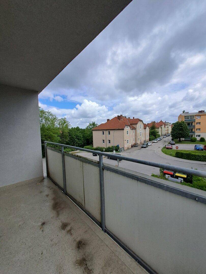 Balkon mit Metallgeländer und Blick auf die umliegende Wohngegend und Straße.