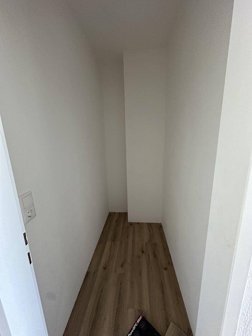 Kleiner, praktischer Abstellraum mit Laminatboden und weißen Wänden für zusätzlichen Stauraum.