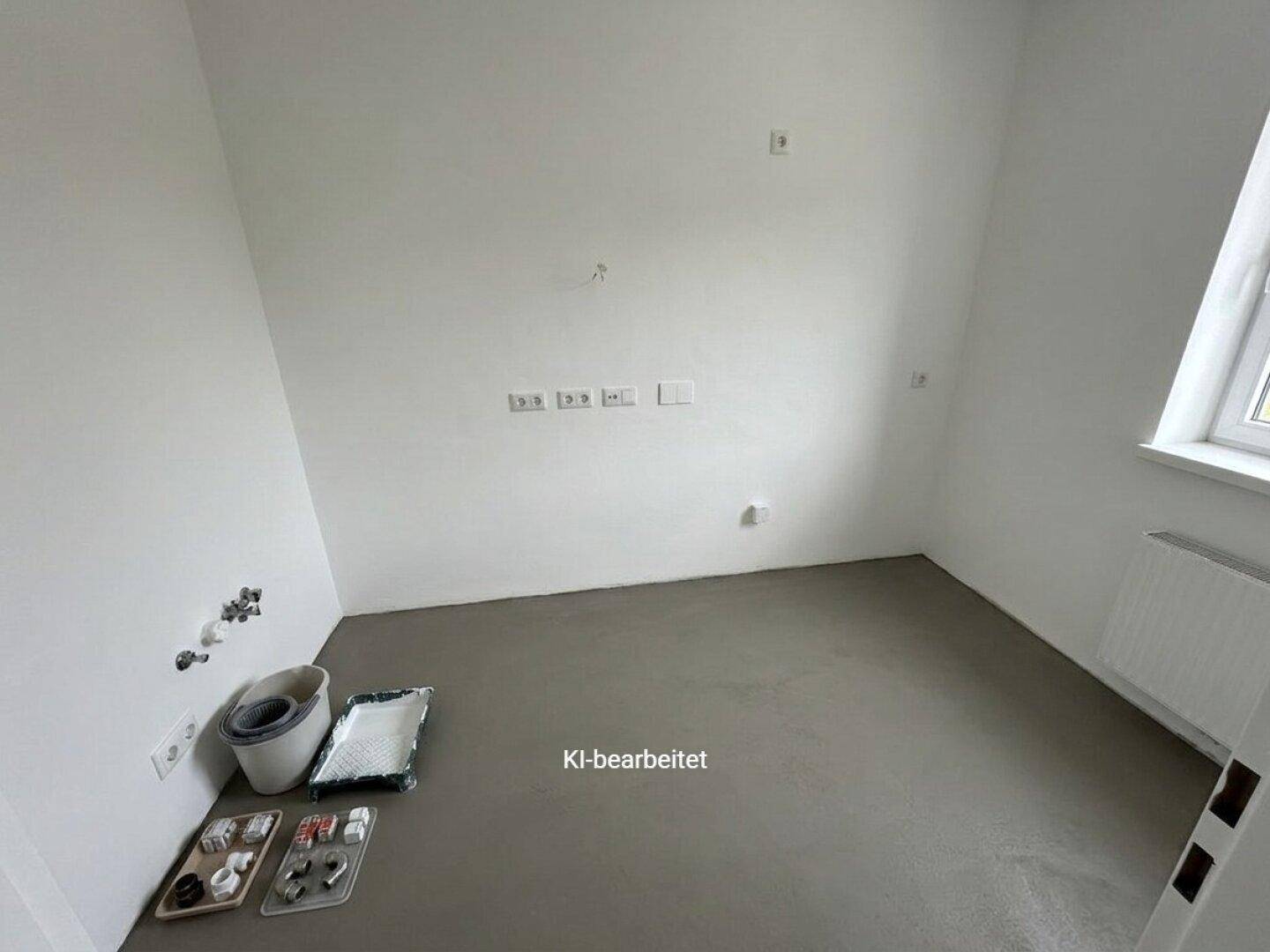 Unfertiges Badezimmer mit Estrichboden, weißen Wänden und sichtbaren Sanitäranschlüssen, bereit für den Ausbau.