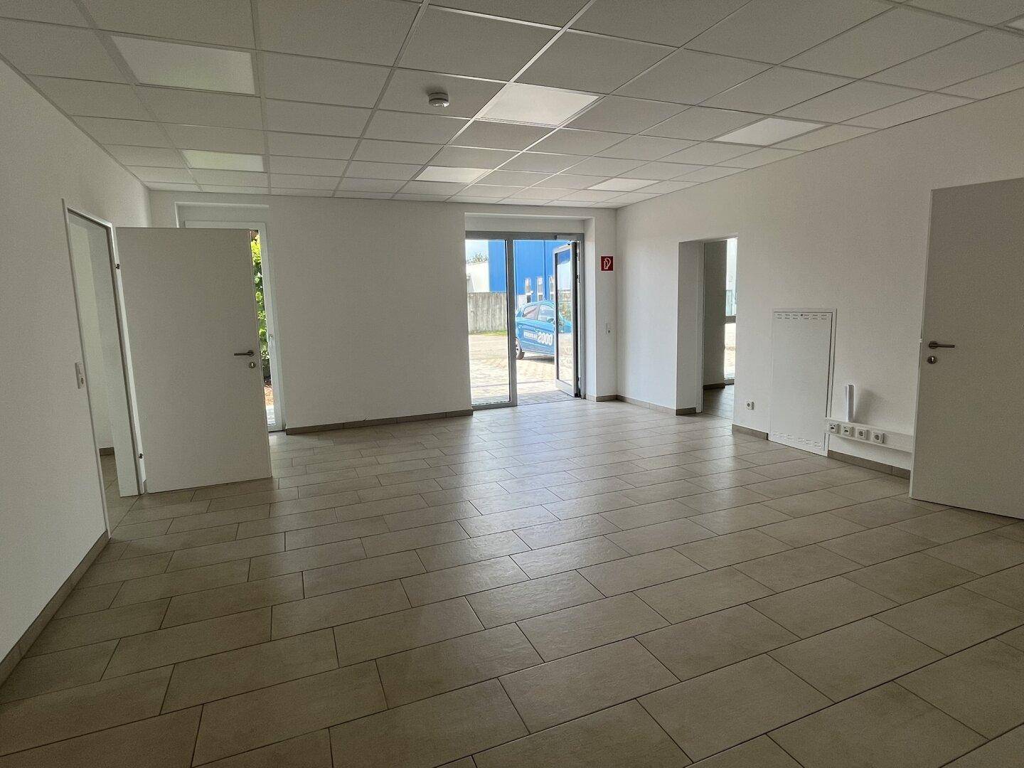 Großer, offener Bürobereich mit mehreren Zugängen und Fliesenboden, ideal für Großraumbüros.