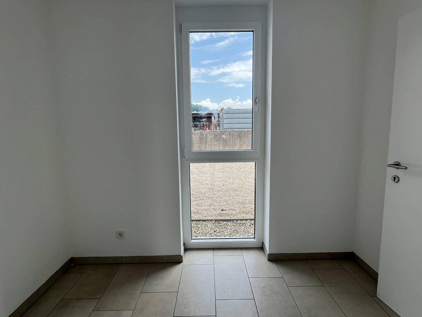 Kleiner Büroraum mit hohem Fenster und Fliesenboden, bietet eine helle und funktionale Arbeitsumgebung.