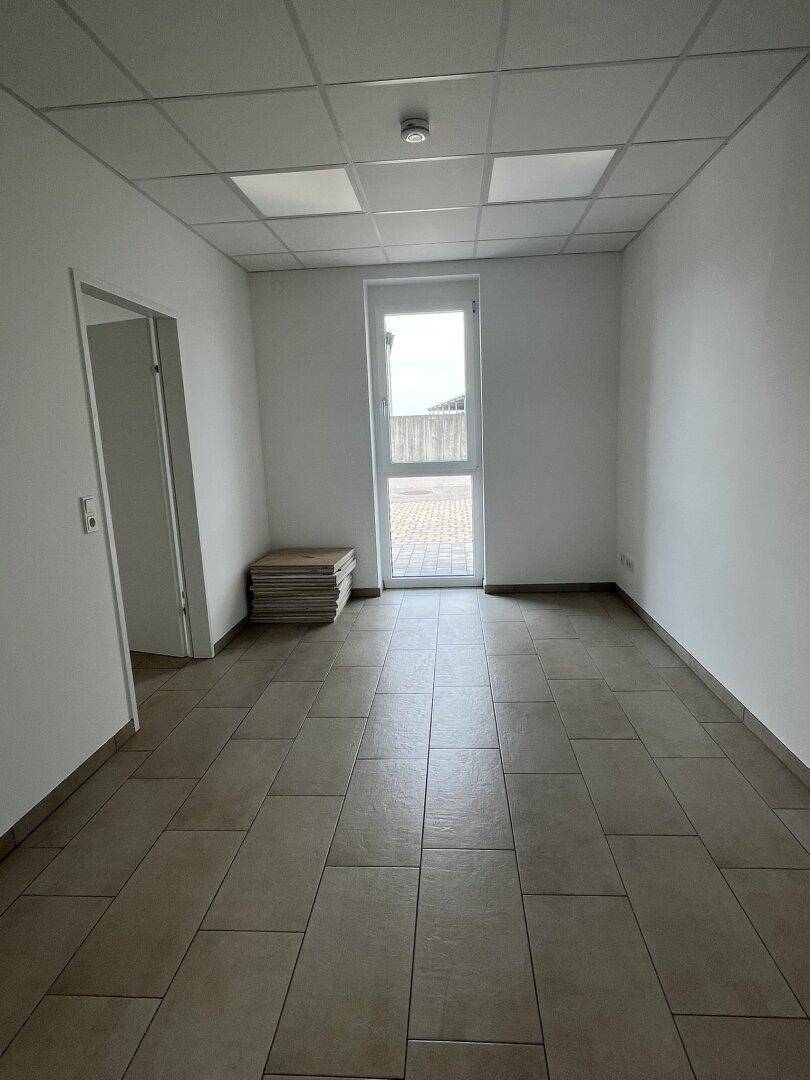 Heller Büroraum mit Fenster und Fliesenboden, bereit für die individuelle Gestaltung.