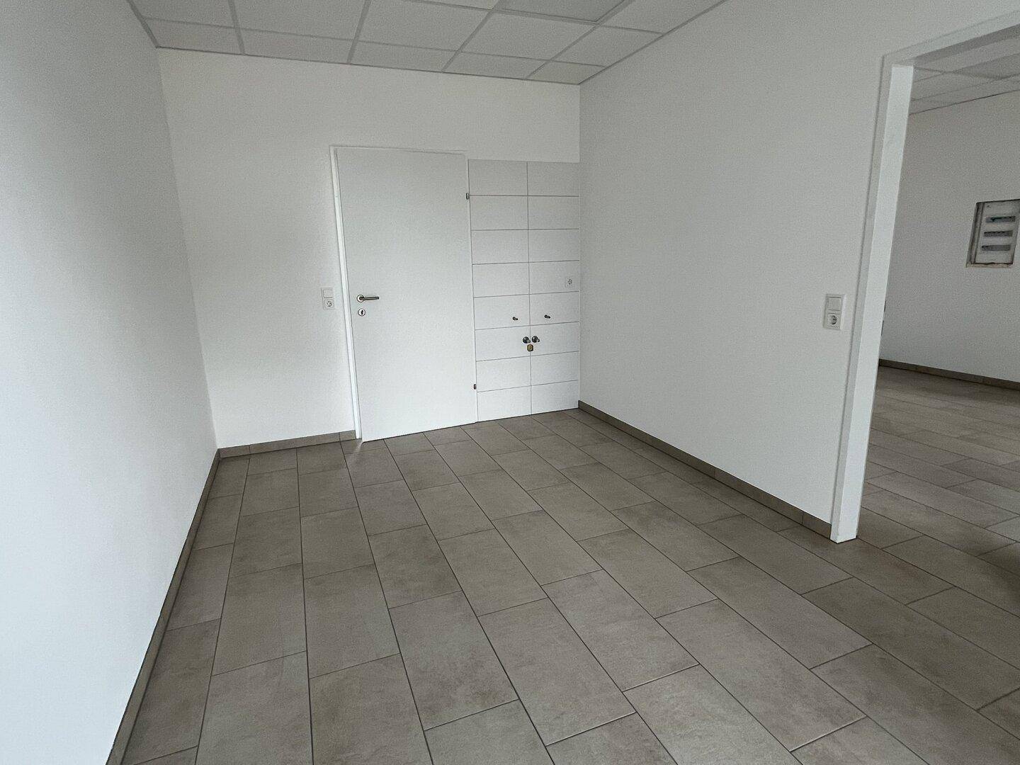 Büroraum mit Fliesenboden und integriertem Schrank, bietet praktische Stauraumlösungen.