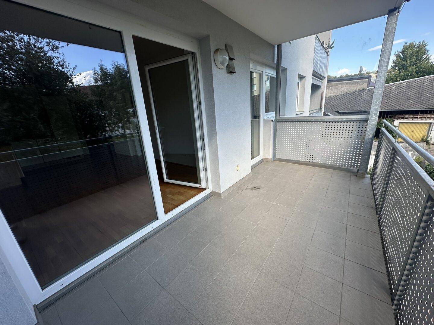 Geräumiger Balkon mit Fliesenboden und Metallgeländer, zugänglich vom Wohnbereich.