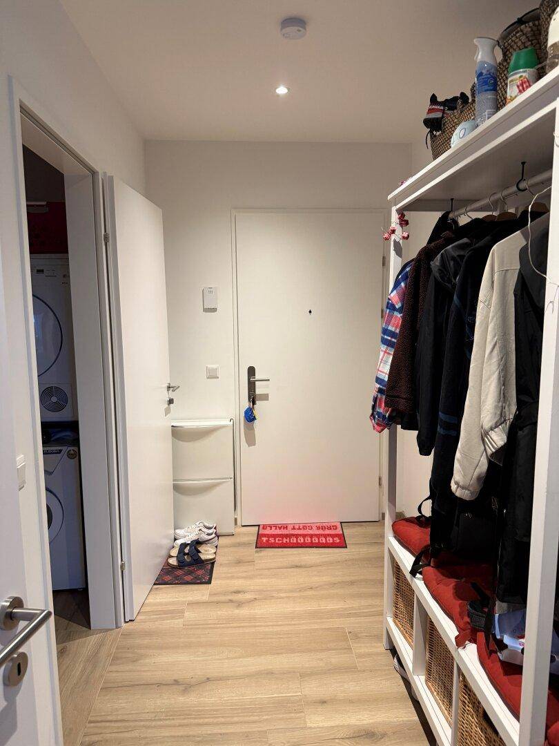 Heller Eingangsbereich mit Garderobe, Laminatboden und Zugang zu weiteren Räumen.