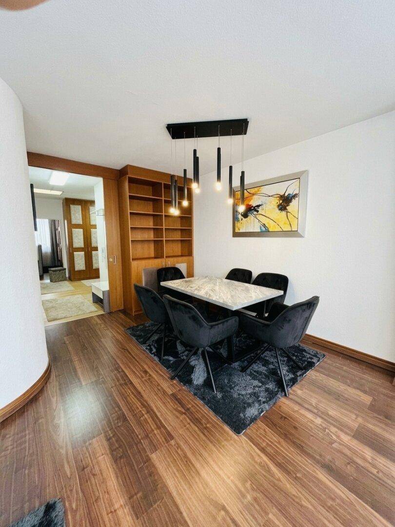 Eleganter Essbereich mit modernem Tisch, schwarzen Stühlen und stilvoller Beleuchtung.