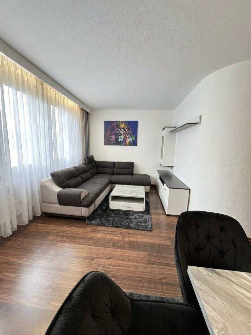 Helles Wohnzimmer mit bequemer Eckcouch, Couchtisch und großen Fenstern.