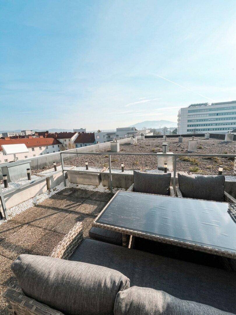 Weitläufige Dachterrasse mit Sitzgelegenheiten und Panoramablick auf die Umgebung und Berge.
