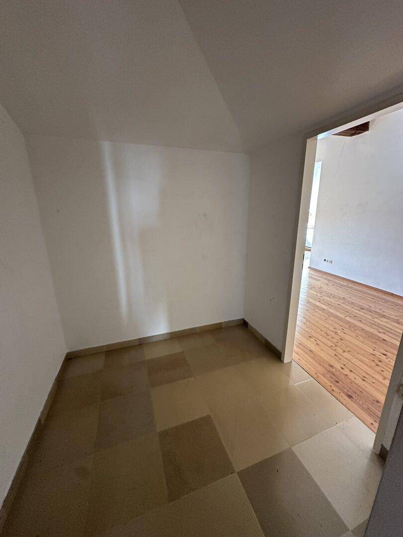 Kleiner Abstellraum mit beigefarbenen Fliesen und Zugang zum Hauptwohnraum.