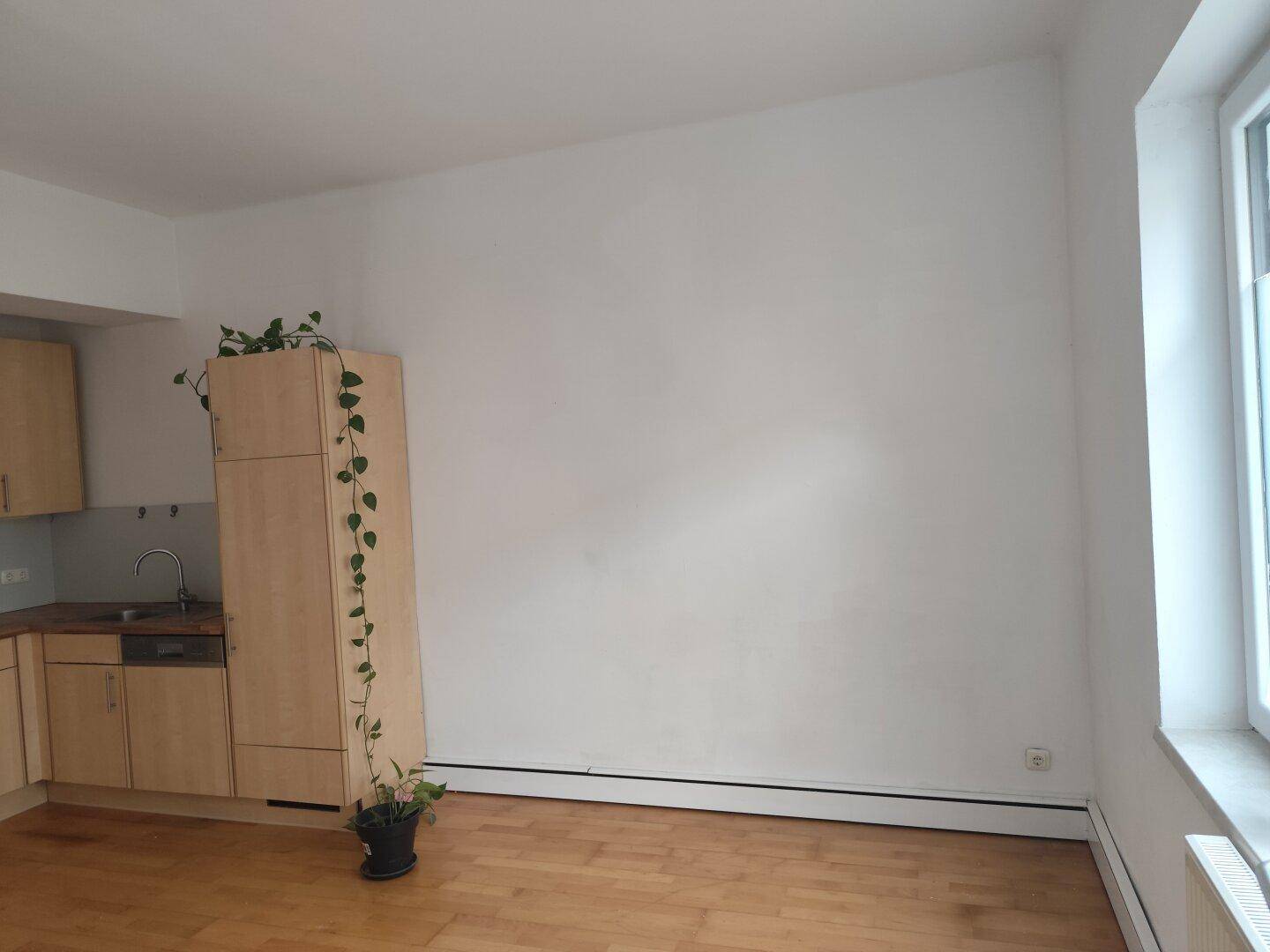Heller Wohnbereich mit integrierter Küchenzeile und Parkettboden, bereit zur individuellen Gestaltung.