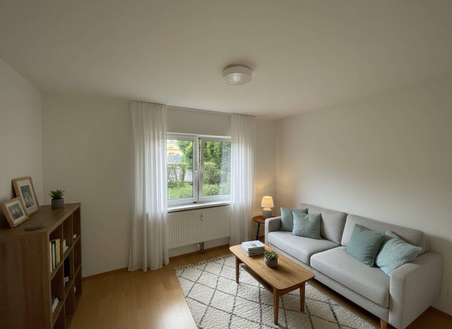 Helles Wohnzimmer mit beigem Sofa, Holztisch und Blick ins Grüne.