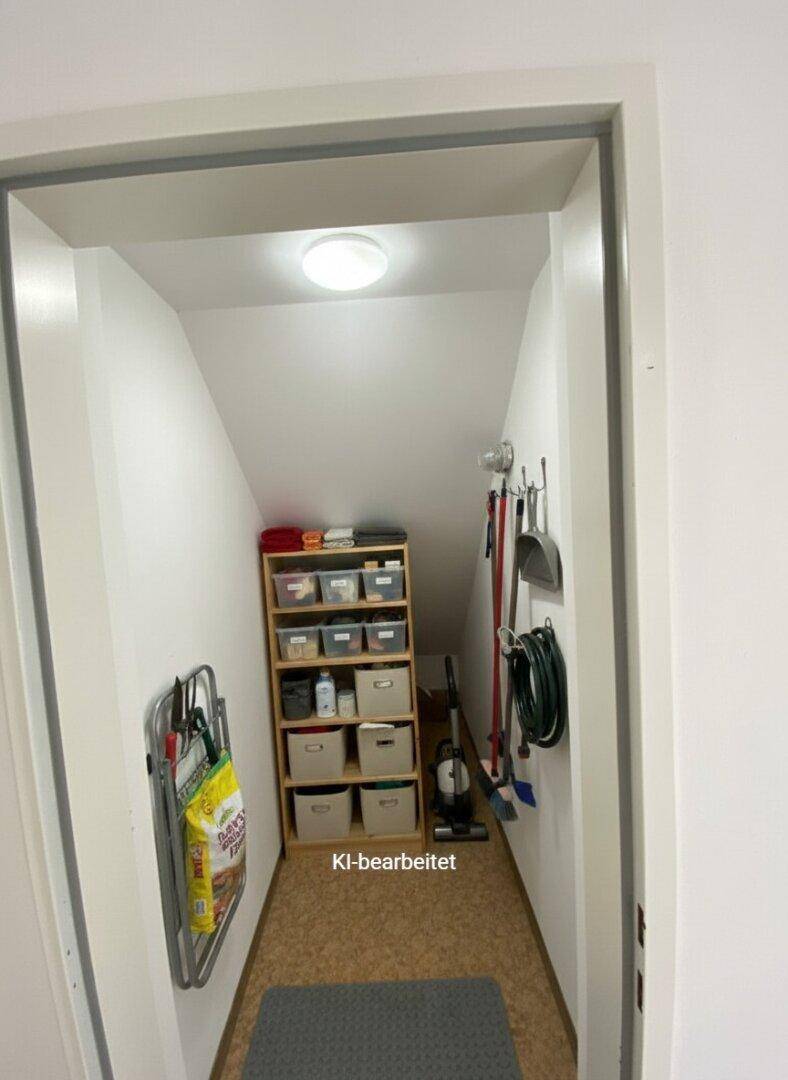 Praktischer Abstellraum unter der Treppe mit Regalen und Reinigungsutensilien.