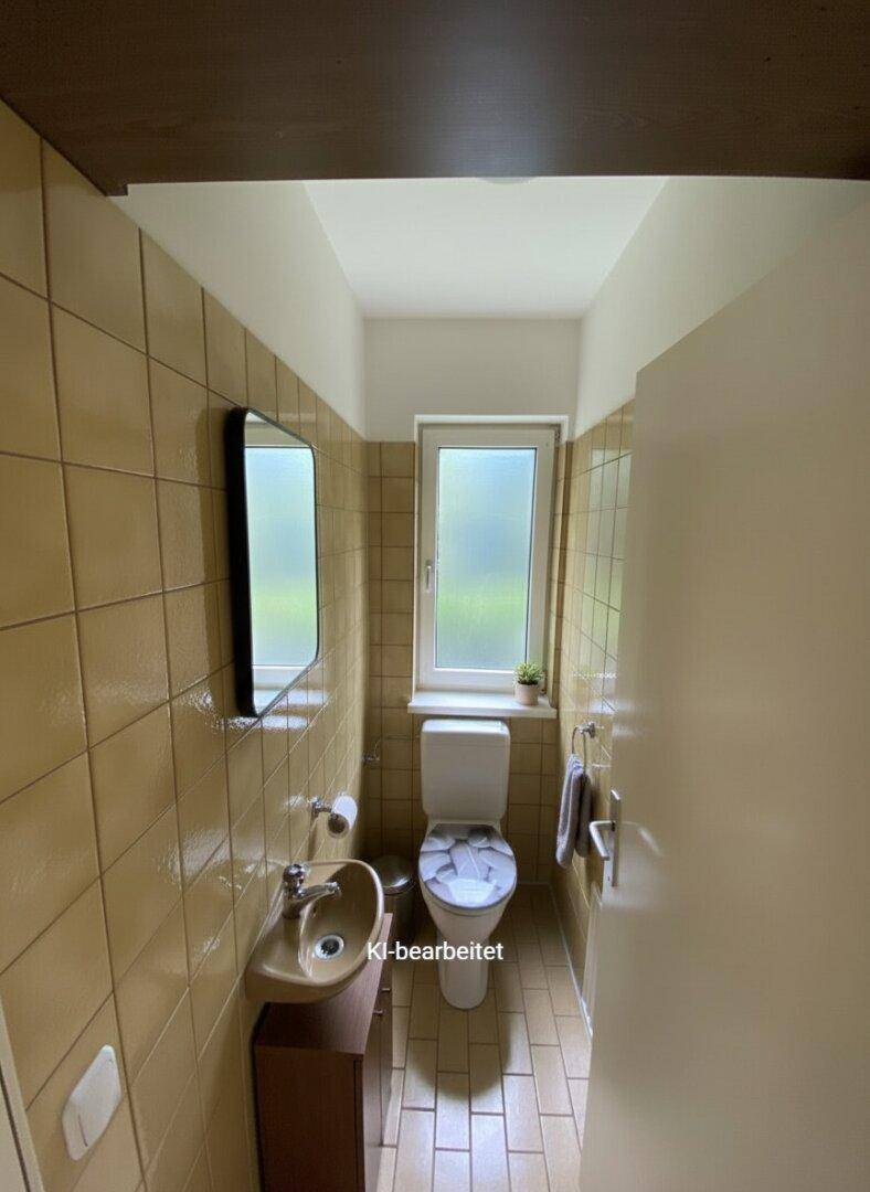 Kleines Gäste-WC mit beigen Fliesen, Fenster und Waschbecken.