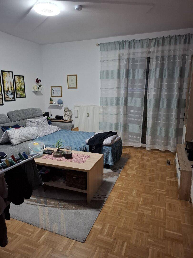 Wohnzimmer mit Sofa, Couchtisch und Zugang zu einem möglichen Balkon oder Terrasse.