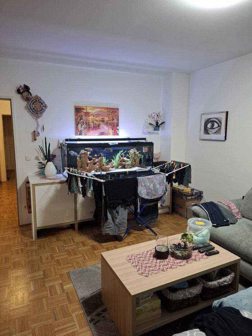 Wohnzimmer mit großem Aquarium, Sofa und Couchtisch, das eine gemütliche Atmosphäre schafft.