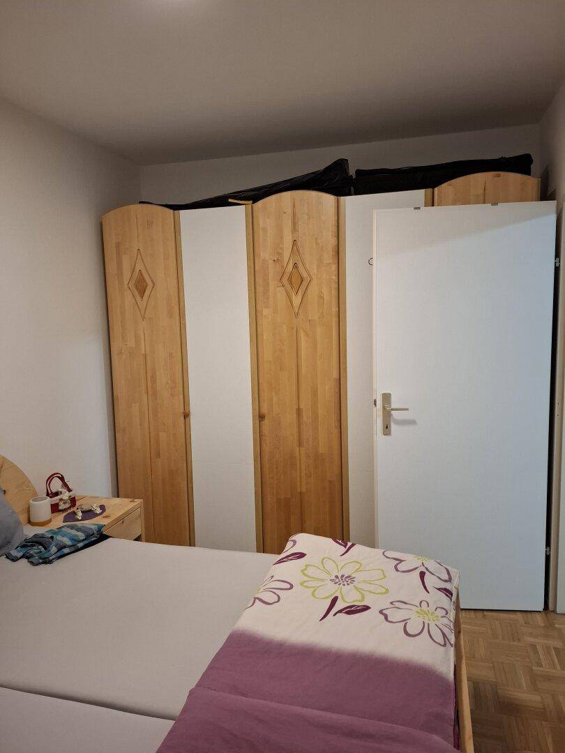 Schlafzimmer mit Holzbett und großem Kleiderschrank, der viel Stauraum bietet.