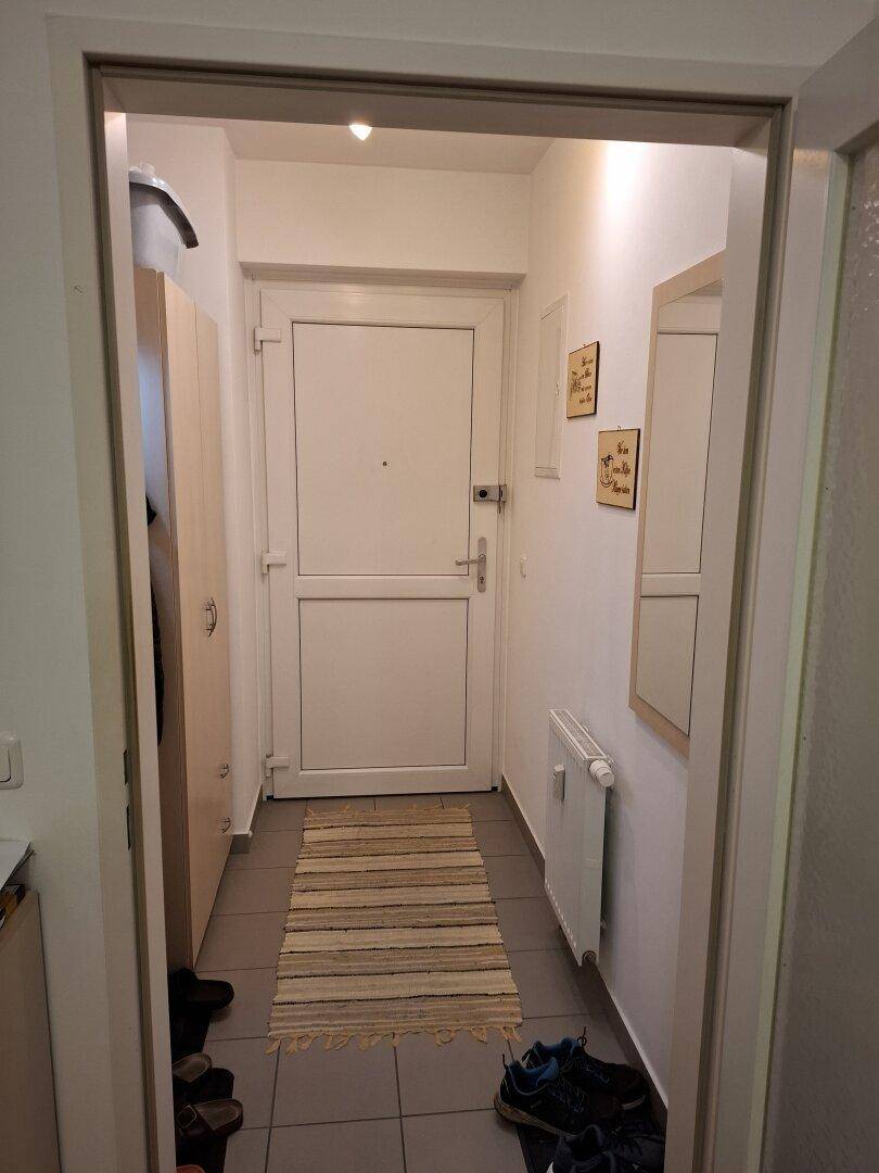 Eingangsbereich mit Haustür, Spiegel und Fliesenboden, der einen freundlichen Empfang bietet.