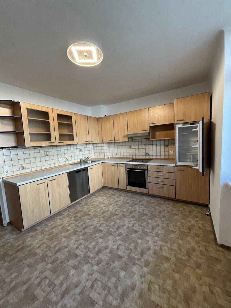 Funktionale Küche mit Holzschränken, Fliesenrückwand und integrierten Geräten wie Geschirrspüler und Backofen.