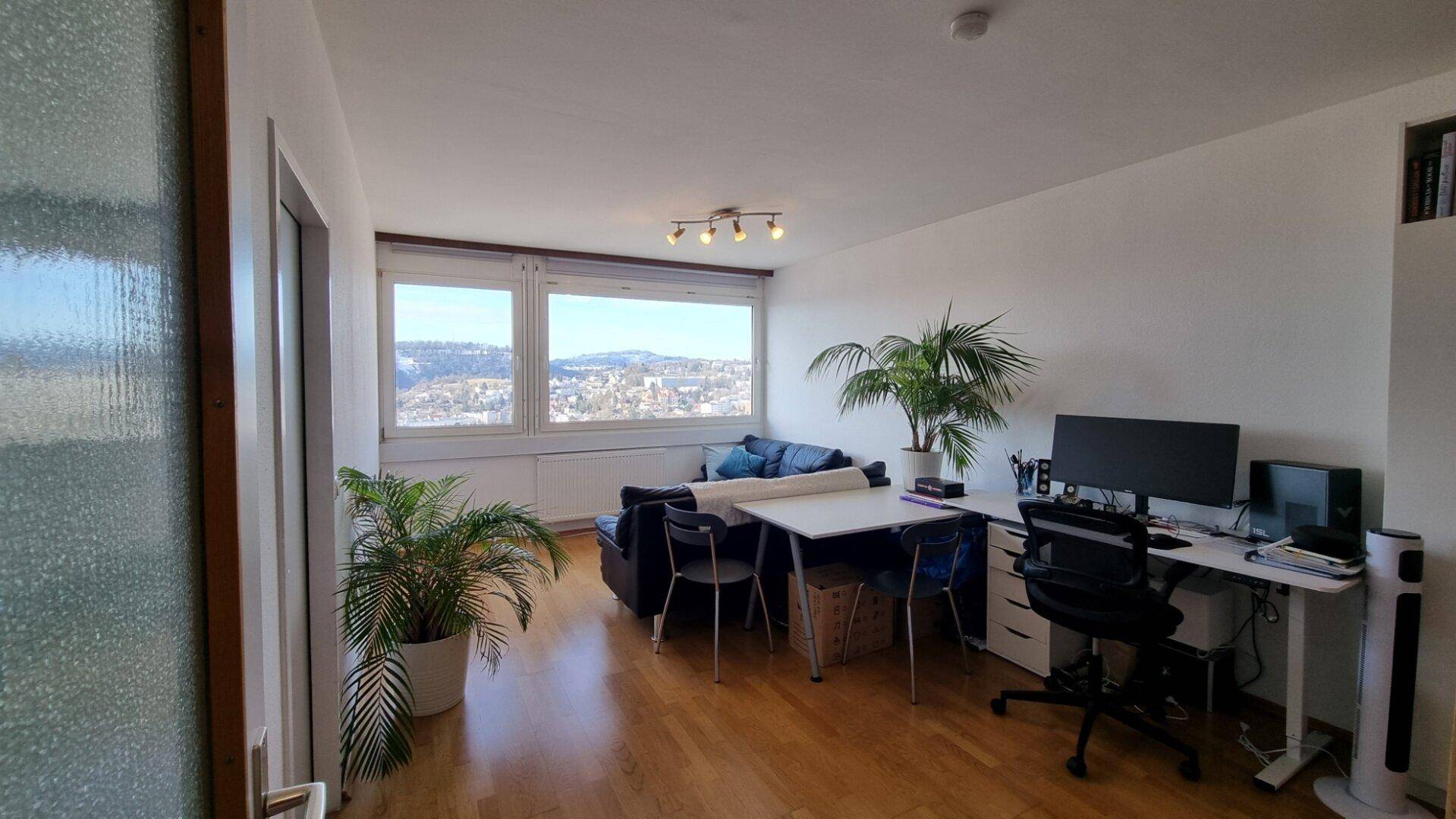 Heller Wohn- und Essbereich mit Arbeitsplatz, Holzboden und Panoramablick.