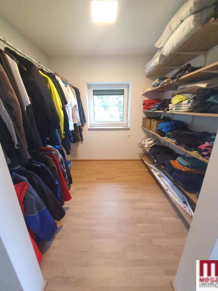 Geräumiger begehbarer Kleiderschrank mit Regalen und Kleiderstangen, gut organisiert.