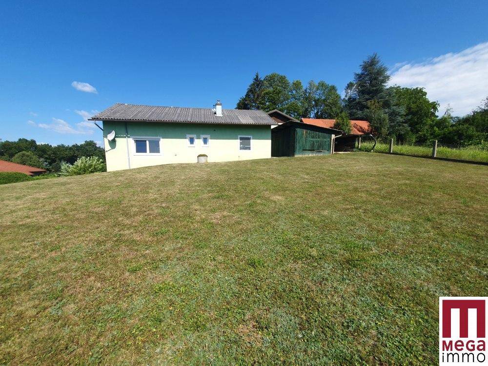 Haus mit grünem Anstrich und Nebengebäude auf einem weitläufigen Grundstück.