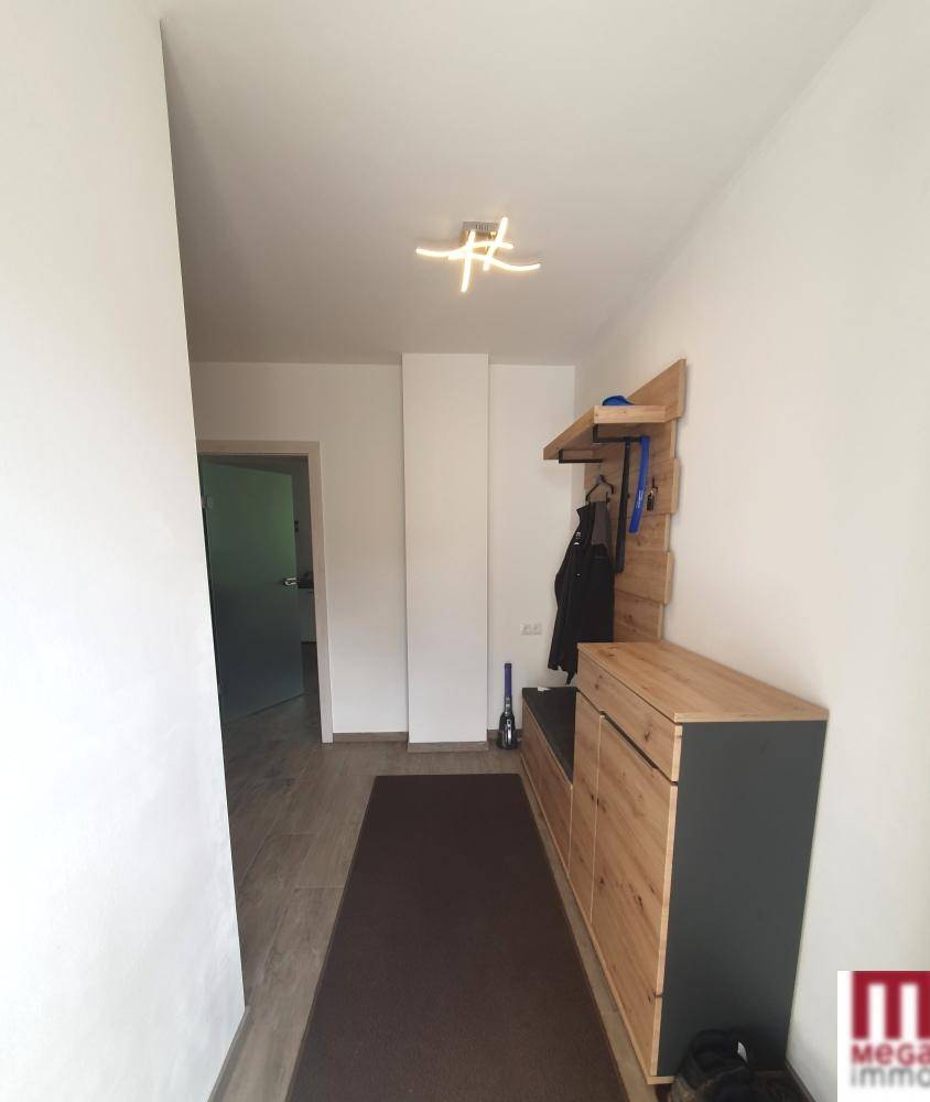 Heller Flur mit moderner Garderobe aus Holz und dunklem Teppichläufer, einladend gestaltet.