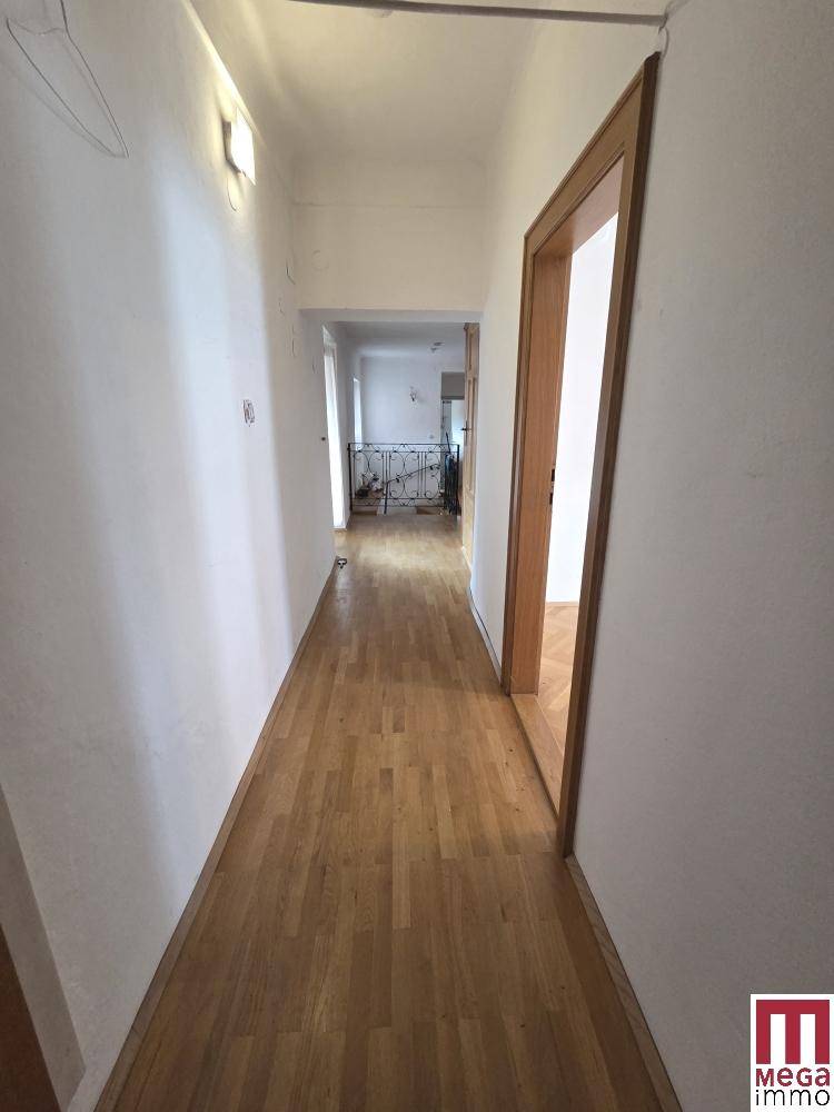Langer Flur mit hellem Parkettboden und Holztüren, der zu weiteren Räumen führt.