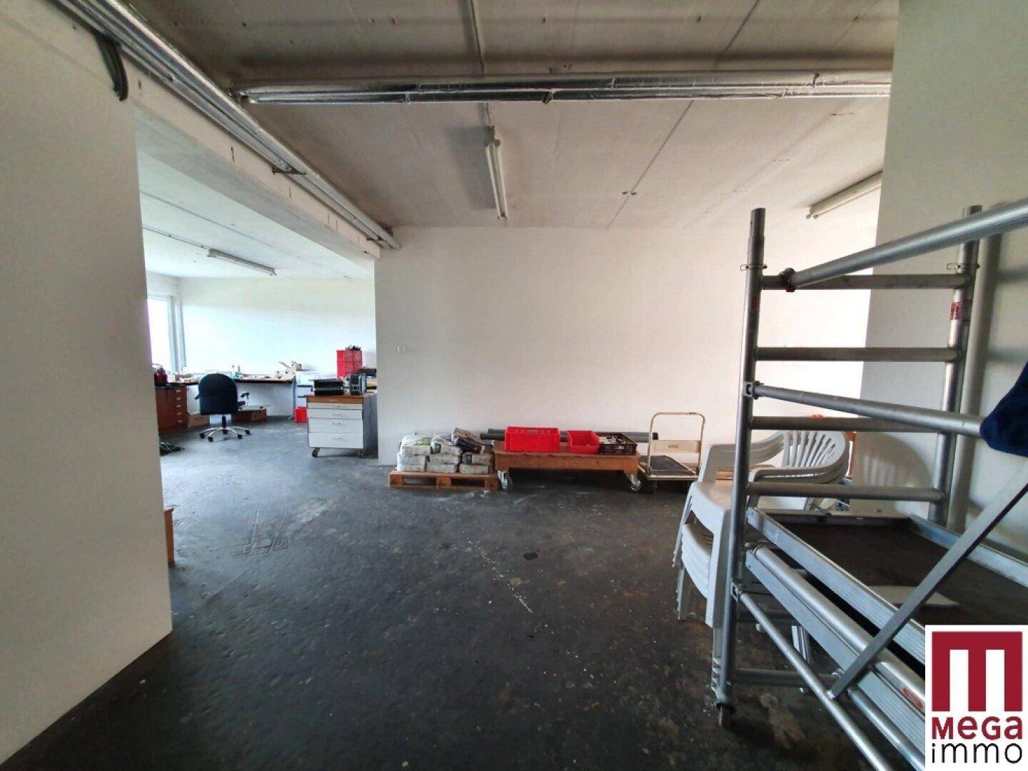 Großer Lagerraum mit Betonboden und Blick auf einen weiteren Arbeitsbereich.