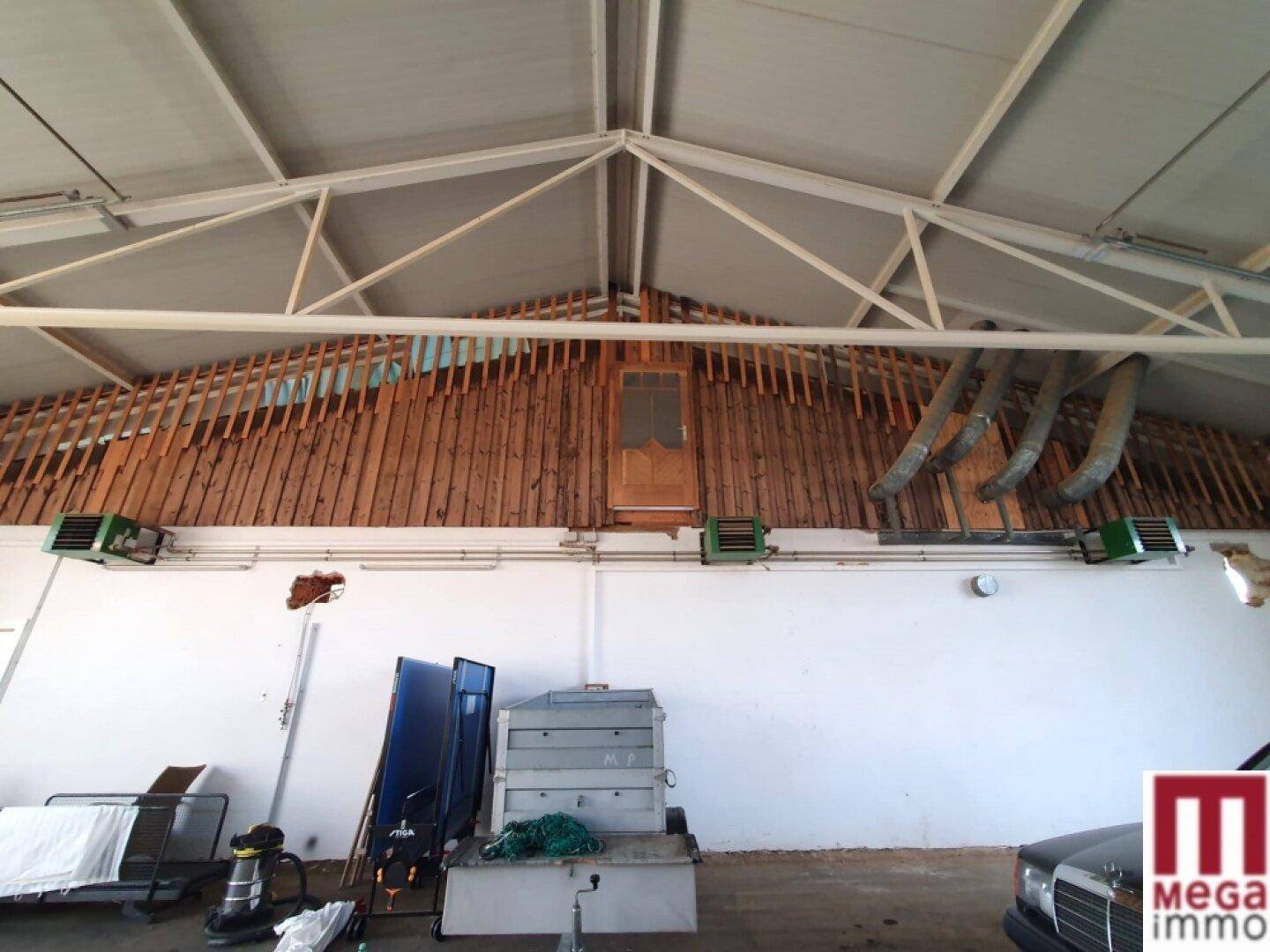 Hohe Lagerhalle mit sichtbaren Dachbalken und Holzverkleidung an der Wand.