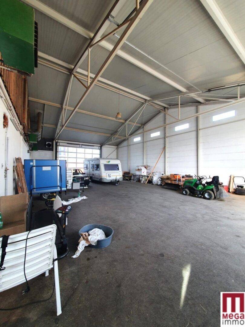Weitläufige Lagerhalle mit hohen Decken, Betonboden und verschiedenen Fahrzeugen.