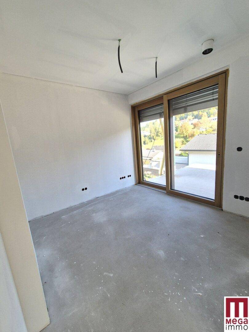 Heller, unmöblierter Raum im Neubau mit Schiebetüren und Blick ins Freie.