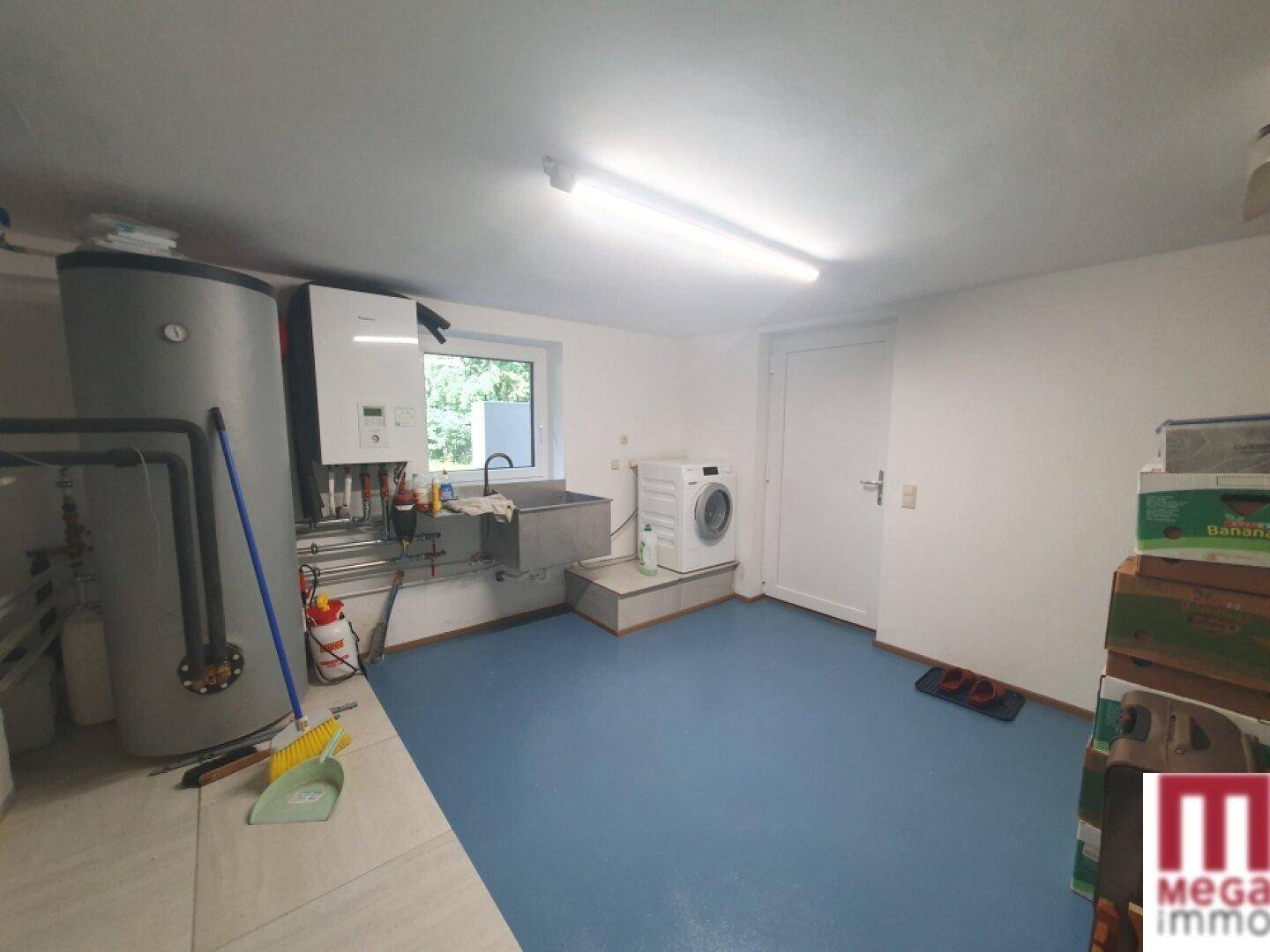 Hauswirtschaftsraum mit Waschmaschine, Warmwasserboiler und Heizungsanlage.