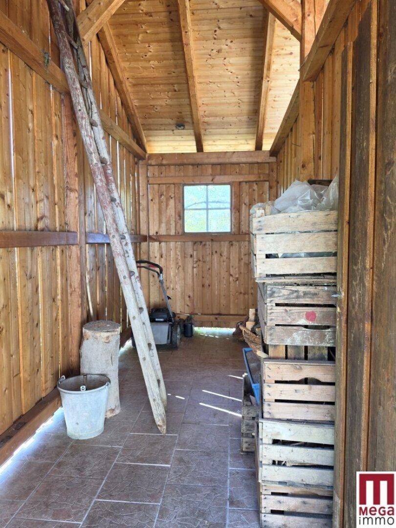Rustikaler Abstellraum mit Holzwänden, Fliesenboden und Stauraum für Gartengeräte und Vorräte.