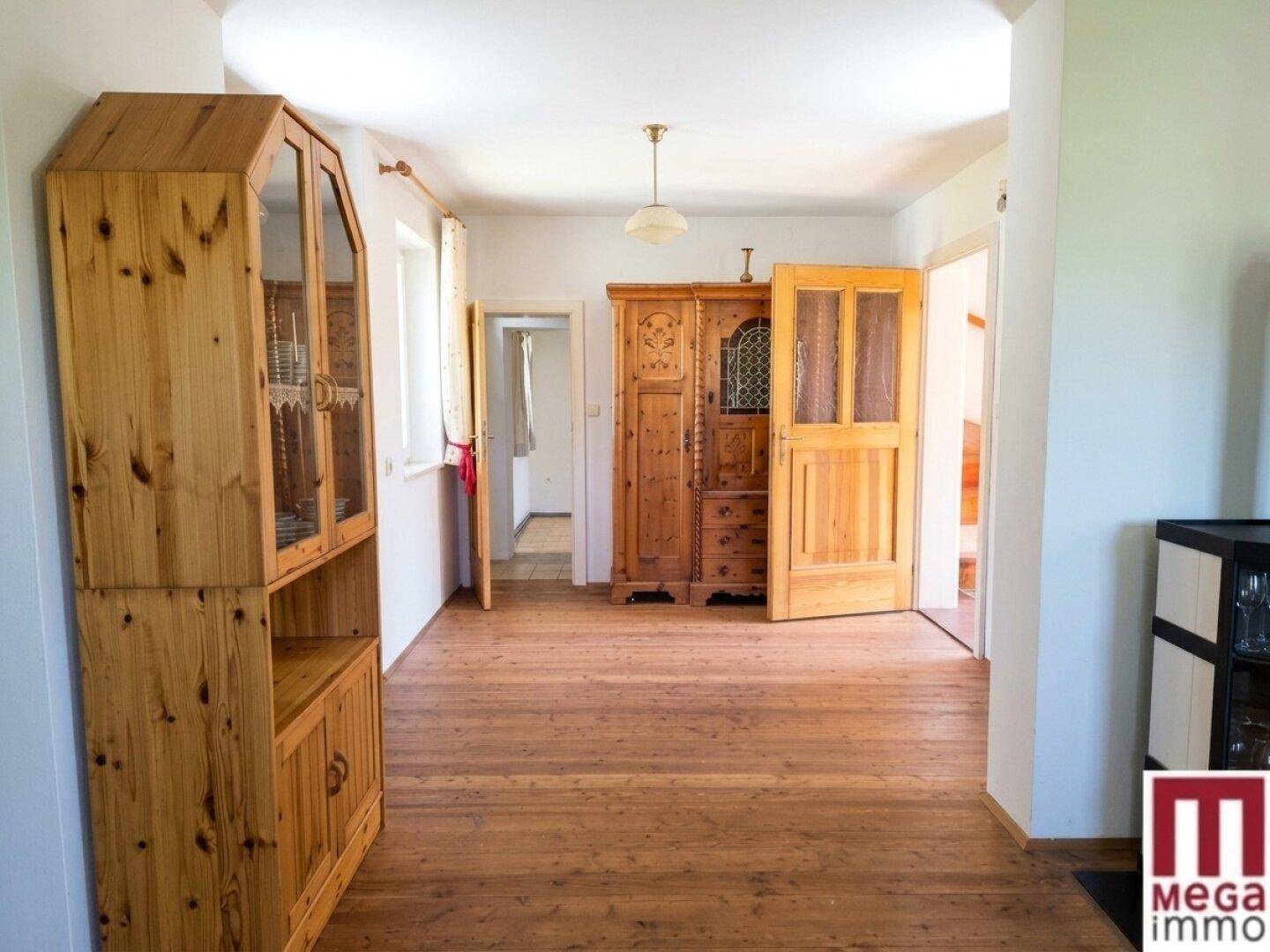 Heller Flur mit traditionellen Holzmöbeln und Holzboden, der zu weiteren Räumen führt.