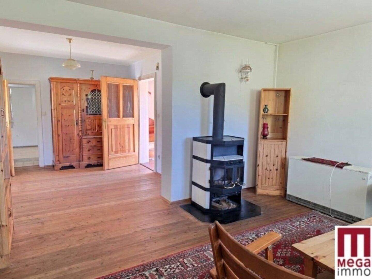 Gemütliches Wohnzimmer mit Holzboden, traditionellem Teppich und einem modernen Holzofen für Wärme.