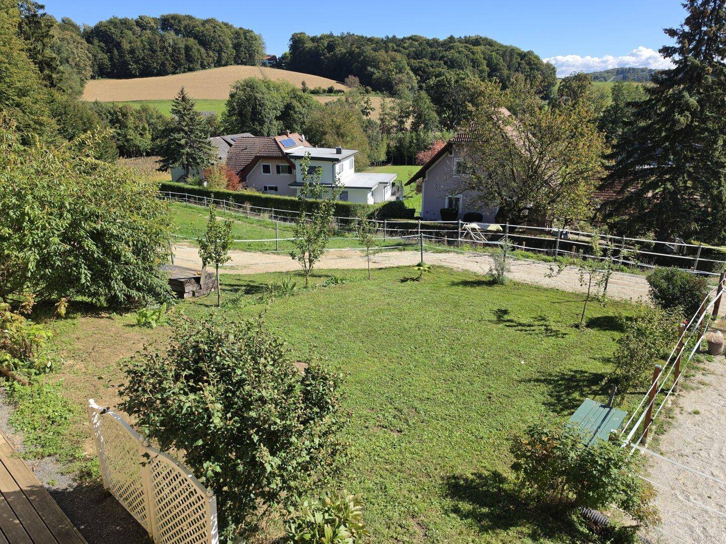 Großer Rasenbereich mit jungen Bäumen und Blick auf die umliegende Landschaft.