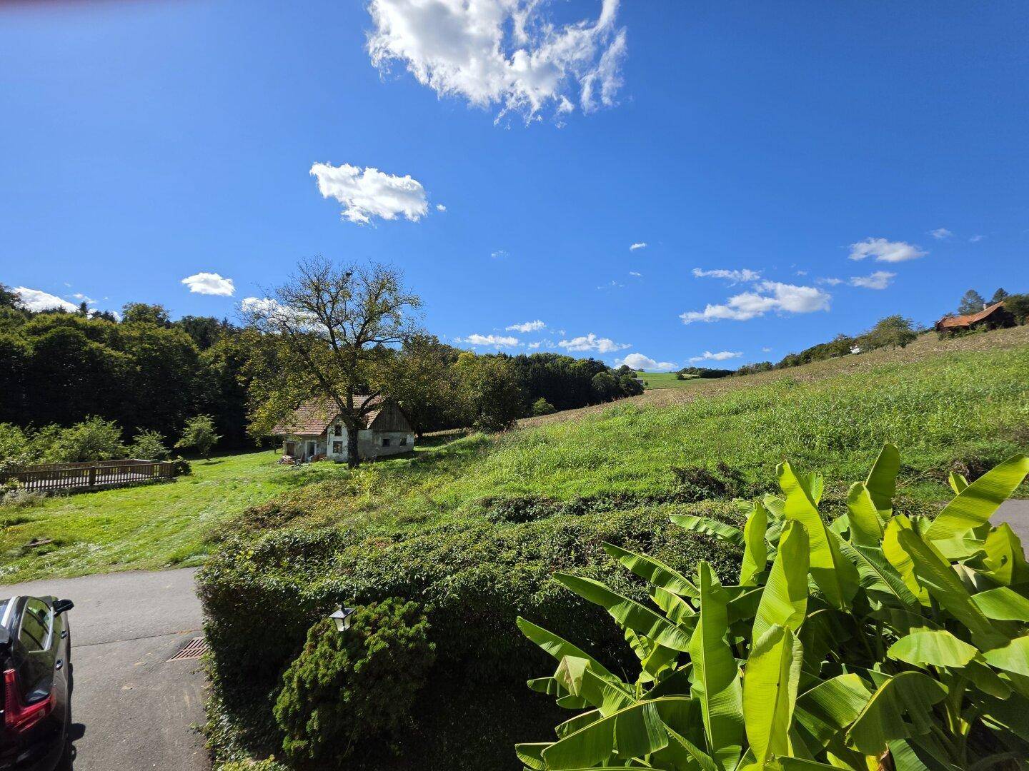 Malerischer Ausblick auf ein kleines Haus in der Ferne und grüne Hügel.