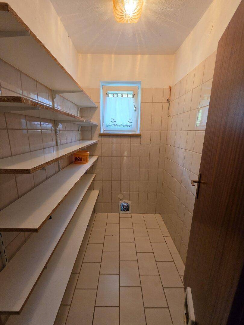 Gefliester Abstellraum mit Regalen und kleinem Fenster für Belüftung.