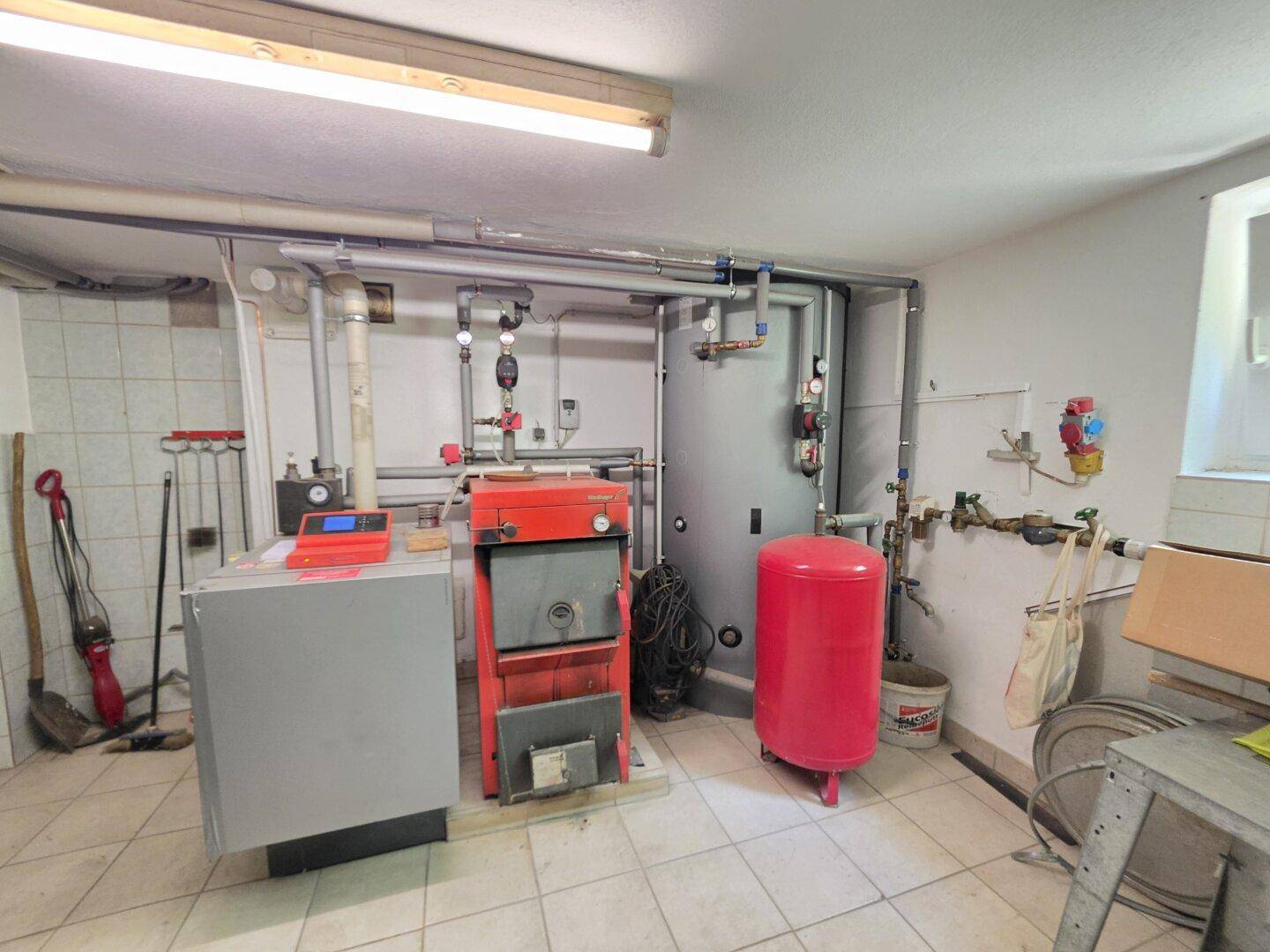 Heizungsraum im Keller mit einem modernen Heizkessel und Warmwasserspeicher.
