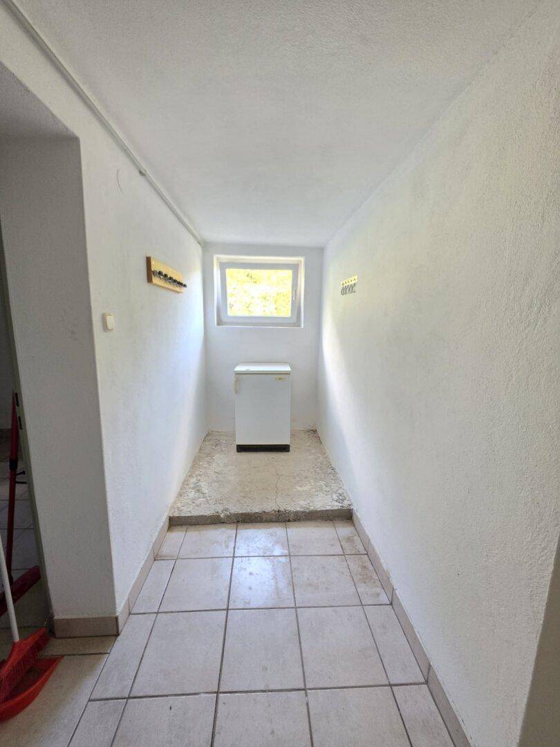 Schmaler Flur im Kellerbereich mit einem Fenster, bietet zusätzlichen Stauraum.
