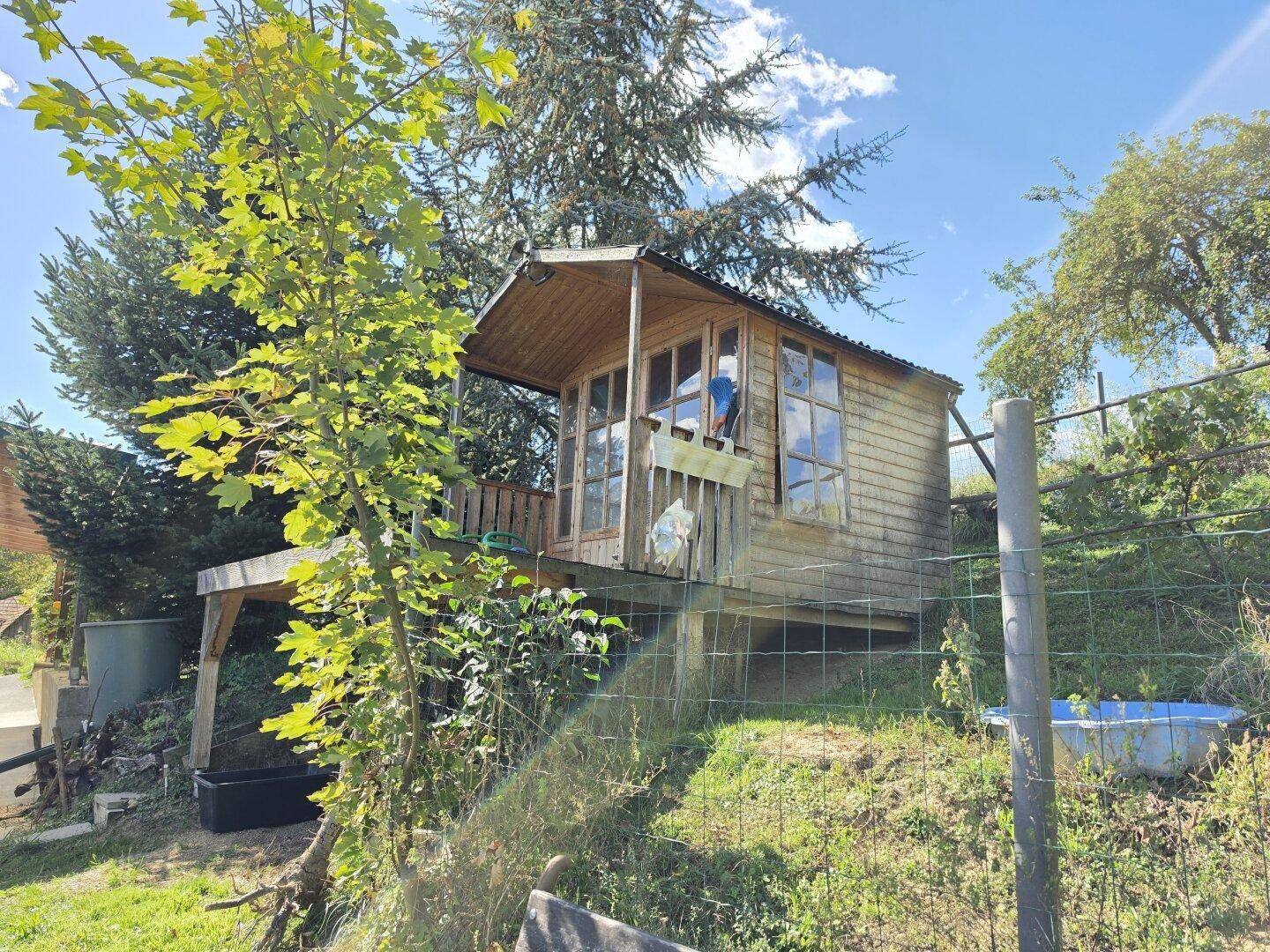 Erhöhtes Holzhaus im Grünen, ideal als Rückzugsort oder Spielhaus im Garten.