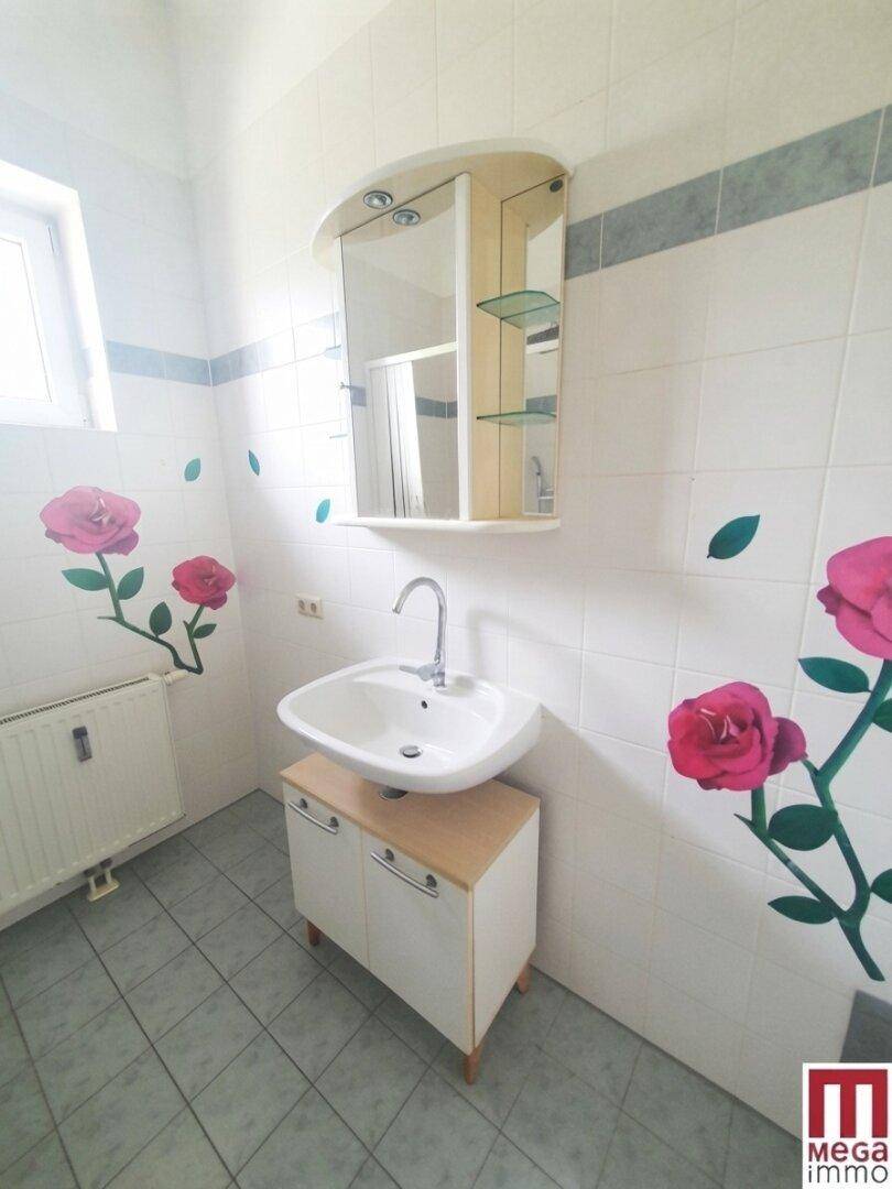 Helles Badezimmer mit Waschbecken, Spiegelschrank und Fenster, verziert mit floralen Aufklebern.