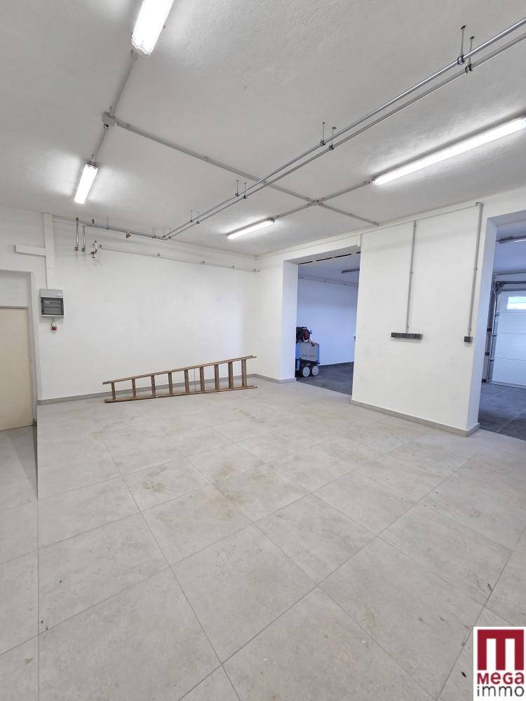 Heller, gefliester Raum mit sichtbaren Leitungen an der Decke und einer Holzleiter.